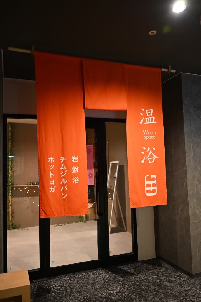 GOOD BLESS GARDEN · SAUNA & STAY — 温浴エリアの暖簾（岩盤浴・チムジルバン・ホットヨガ）